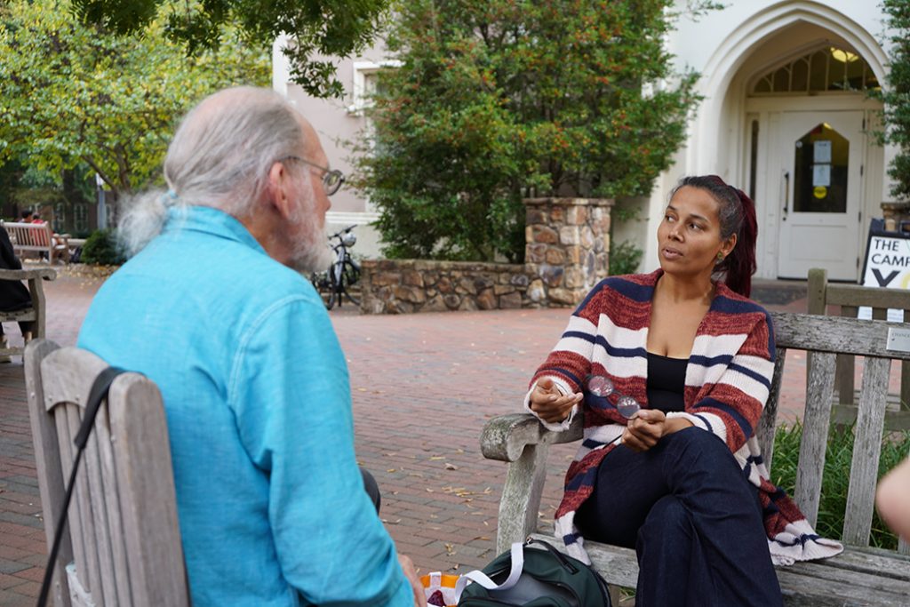 Two seated figures face one another in conversation.